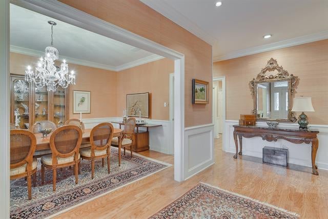 Formal dining room with a crystal chandelier, hardwood floors, and an ornate console and mirror in the adjoining foyer.