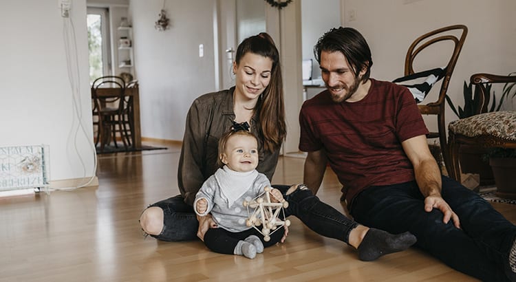 A photo of a happy family, with a child sitting on the floor playing, indicating lifestyle or family-oriented content.