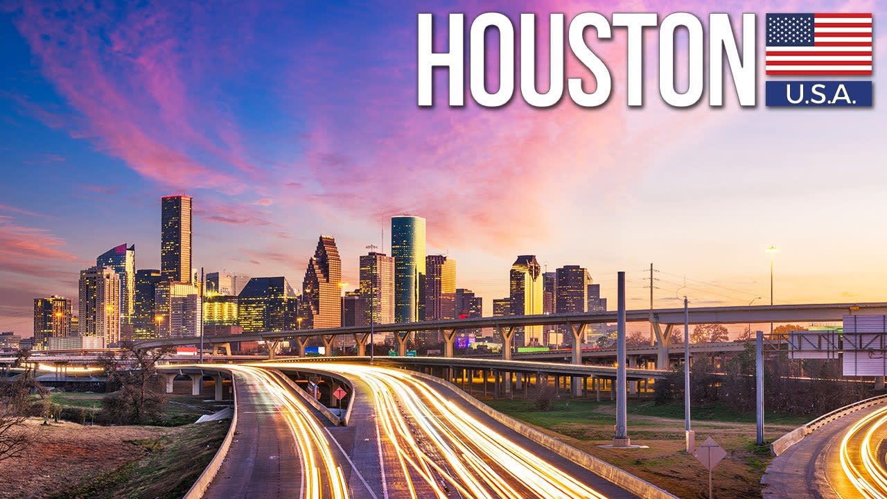 Houston skyline at dusk above elevated highways with streaks of traffic lights.
