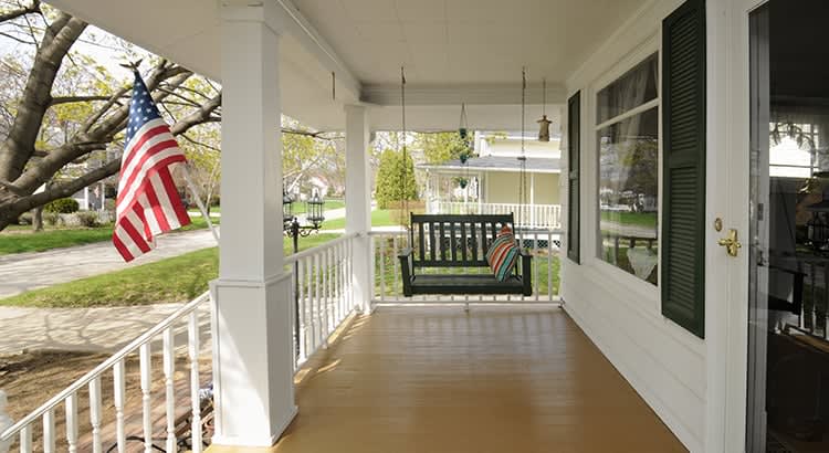 A front porch with an American flag – possibly depicting the traditional or suburban American home lifestyle, with a peaceful front porch scene.