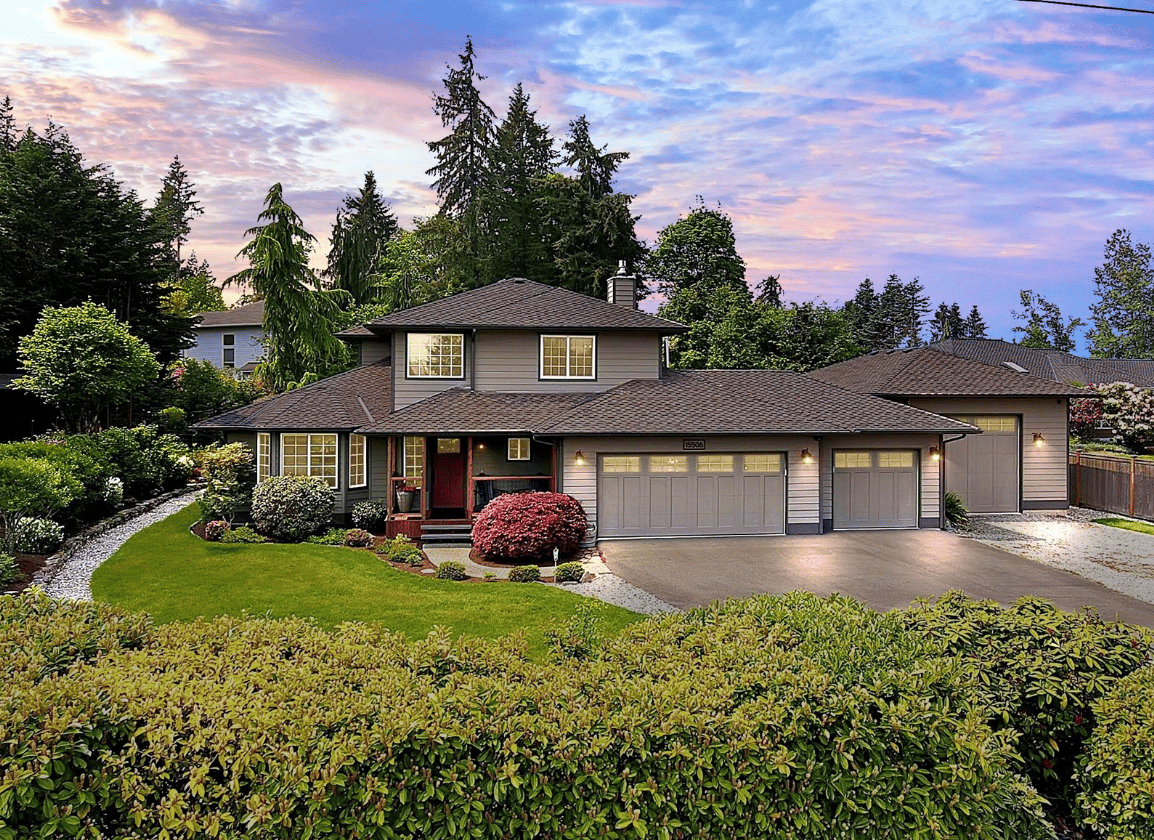 front of grey home with driveway and well kept yard