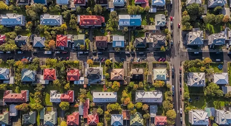 A colorful aerial view of houses in a neighborhood, displaying a variety of rooftops and tree-lined streets.