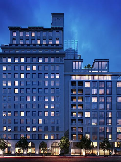 Multi-story building at dusk with illuminated windows and arched street-level entrances.