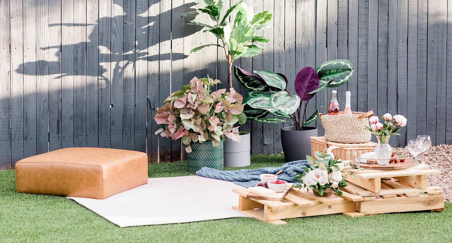 Outdoor patio picnic with flowers, drinks, and snacks arranged on low pallet tables