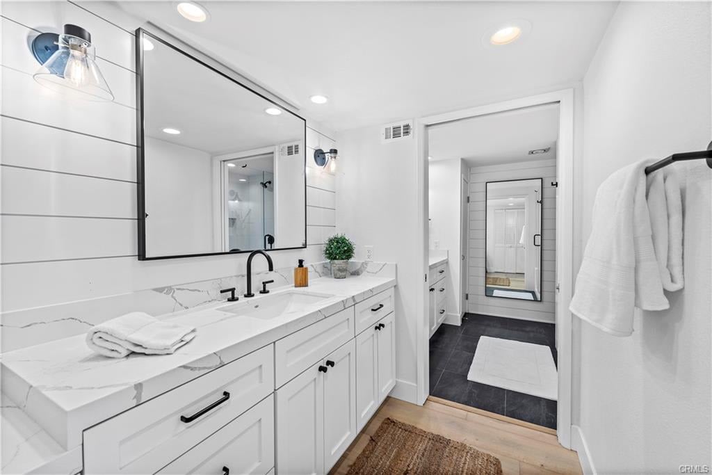 Bright bathroom with a marble vanity, black fixtures, large mirror, and tiled shower area.