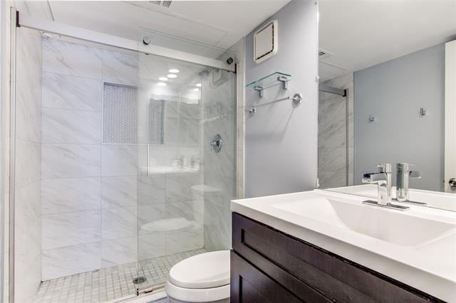 Bathroom with a glass-enclosed tiled shower and dark wood vanity.