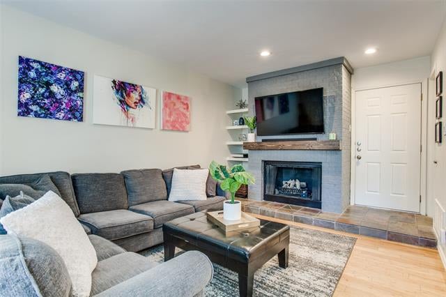 Living room with a gray sectional, stone fireplace, wall-mounted television, and colorful artwork.