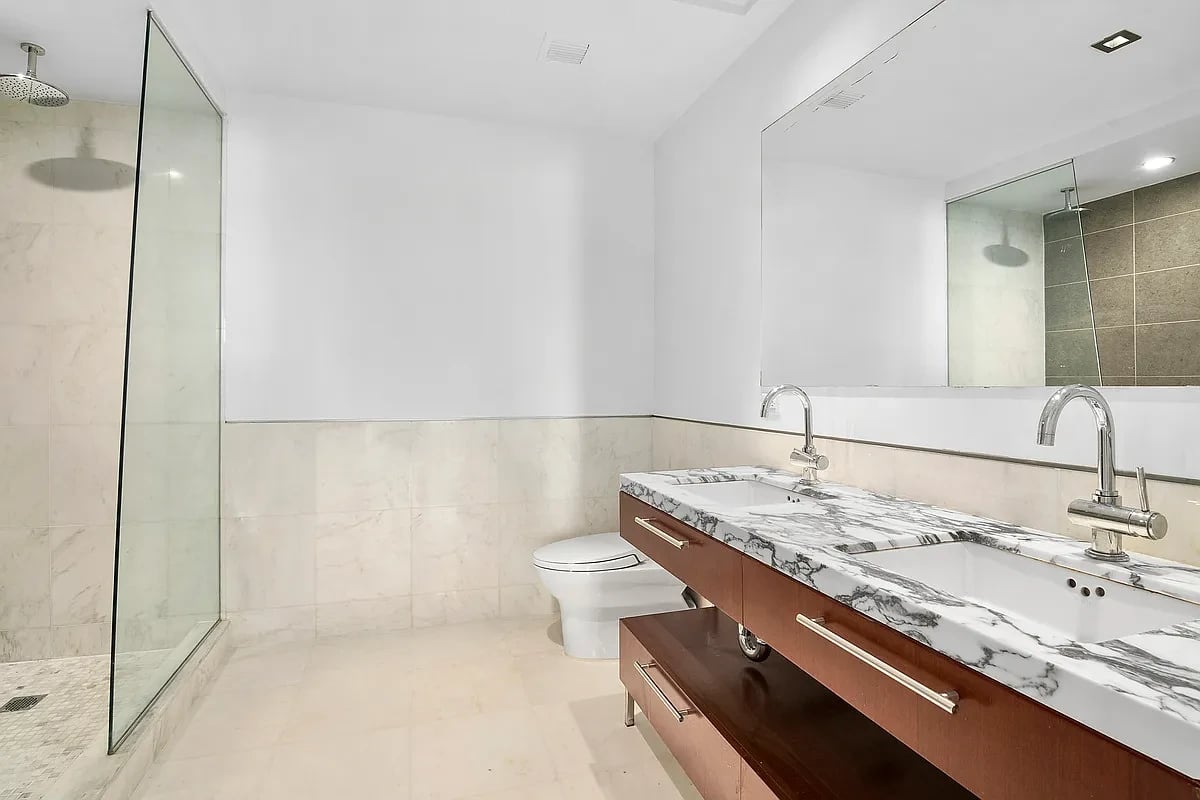 Modern bathroom with a glass shower and long marble double vanity.