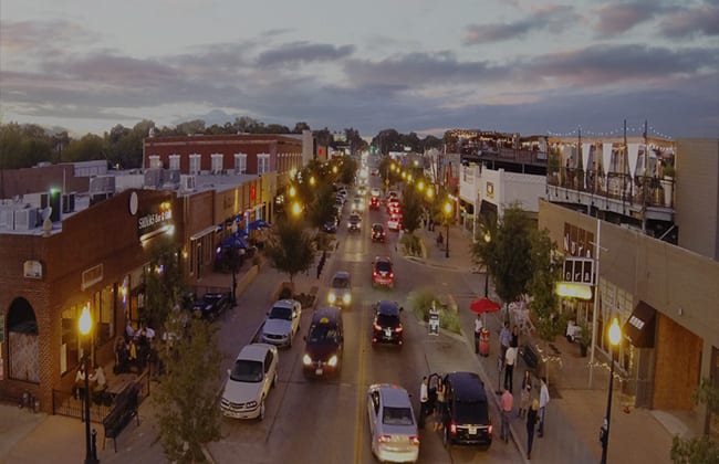 An aerial view of a busy city street at night with cars on the street in Lower Greenville Dallas