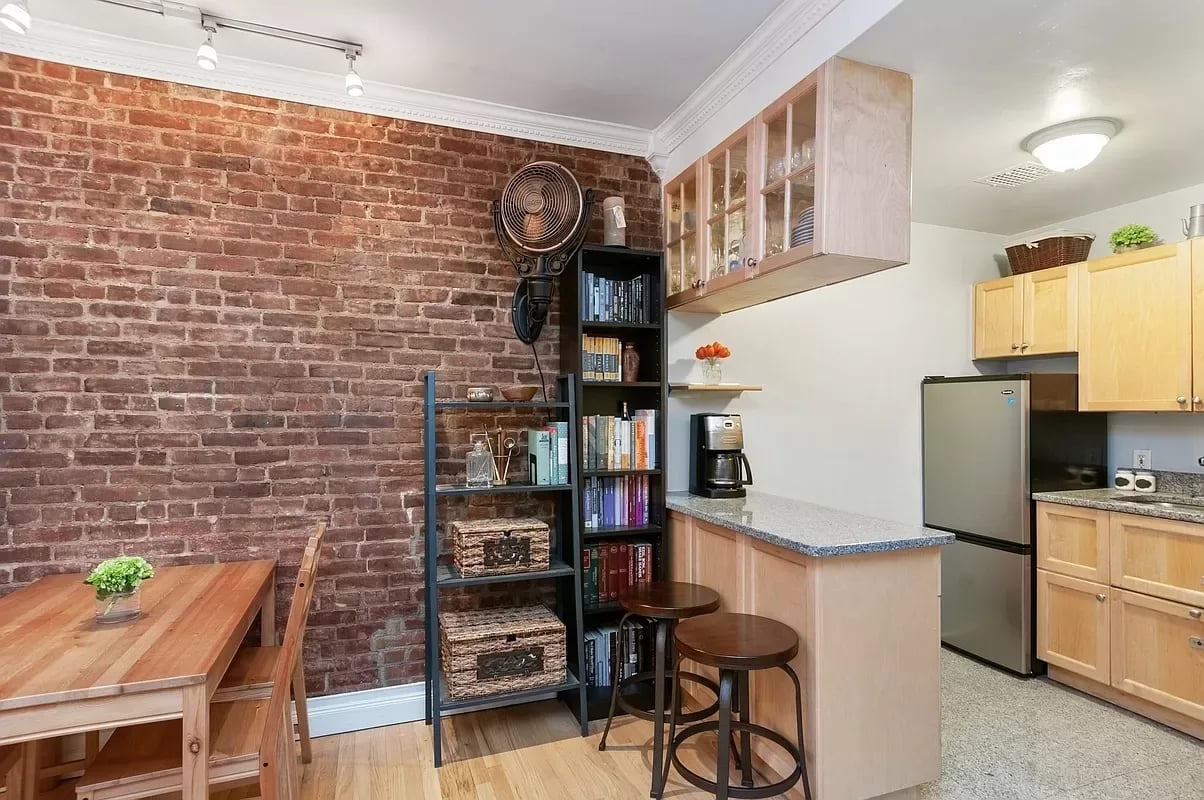 Kitchen with exposed brick wall, breakfast bar, and adjoining dining area.