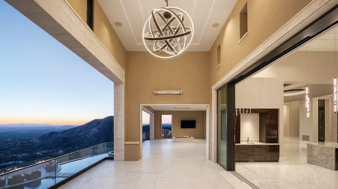 Spacious luxury home interior with modern lighting and expansive mountain views at dusk.