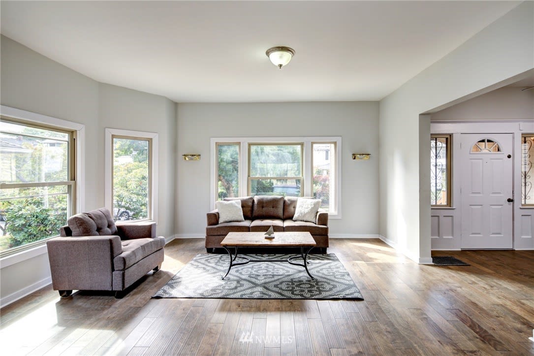 Living room with two sofas, a patterned rug, and large windows overlooking greenery.