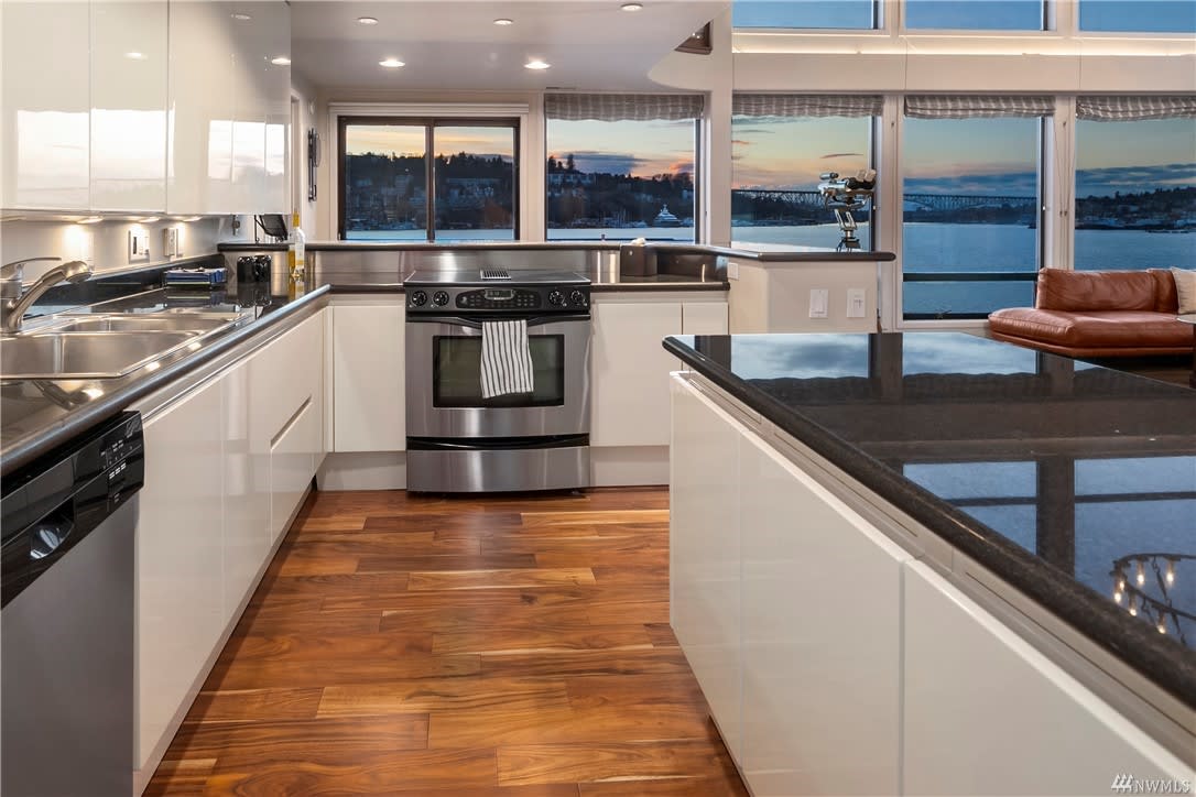 Modern kitchen with stainless steel appliances and rich wooden floors in a luxury condo with a relaxing water view.