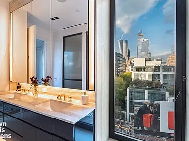Bathroom vanity with dark cabinetry and a window overlooking city buildings.