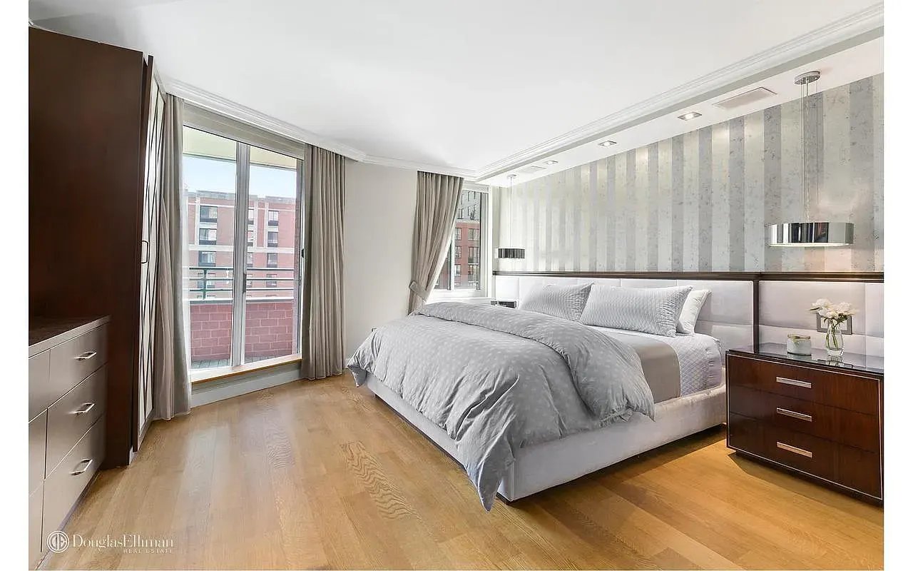 Bedroom with pale gray bedding, a striped accent wall, and sliding glass doors to a balcony.