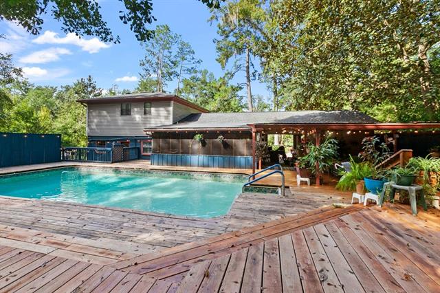 A house with a spacious backyard in 2045 Wahalaw featuring a large wooden deck and a swimming pool. The area is surrounded by trees, providing a private and relaxing environment.