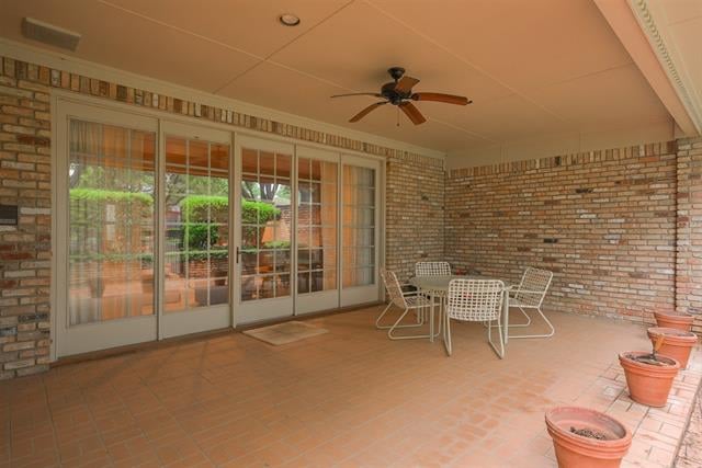 Covered brick patio with terracotta tile, sliding glass doors, white metal furniture, and potted plants.