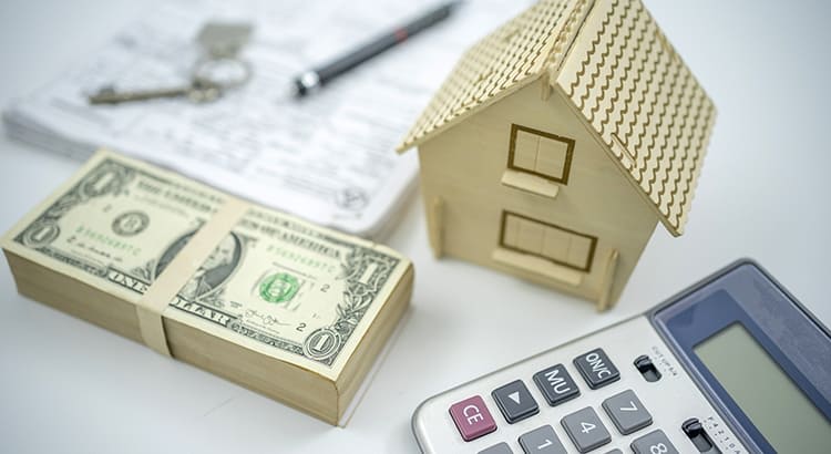 homeownership and the financial considerations involved in purchasing a home. The combination of the house model, cash, and calculator underscores the importance of budgeting and financial planning in real estate. 