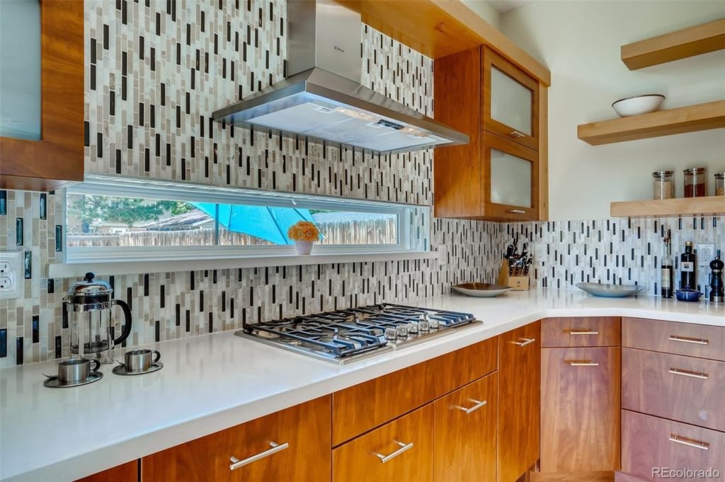 Modern kitchen with warm wood cabinets, a gas cooktop, and a geometric tile backsplash.