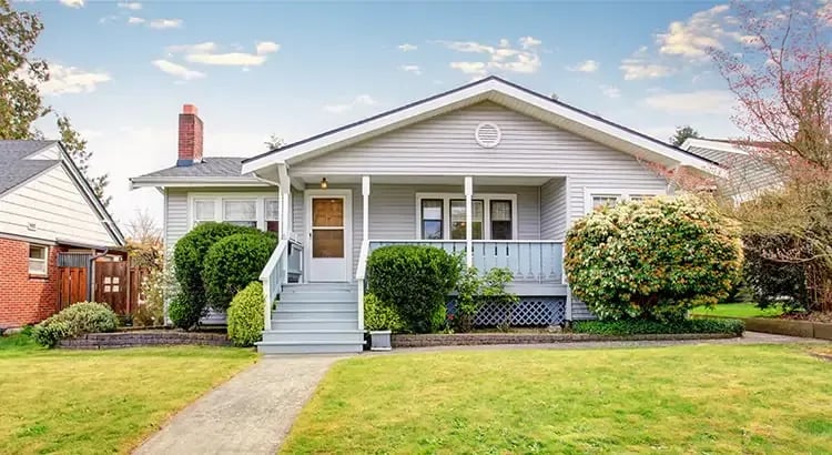 A suburban house with a well-kept lawn and a clear path leading to the front door. The house has a traditional design with a gabled roof and a porch.