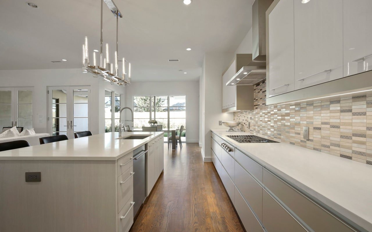 Sleek and stylish custom kitchen with a large island, modern appliances, and pendant lights by S&R Development.