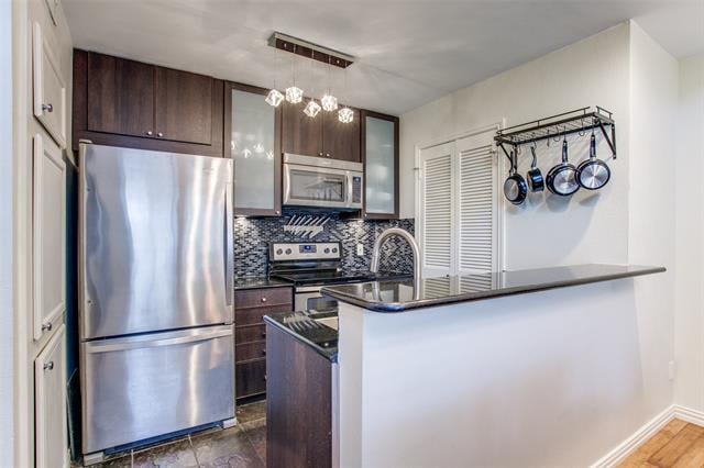 Modern kitchen with dark wood cabinets, stainless steel appliances, mosaic backsplash, and a wide breakfast bar.