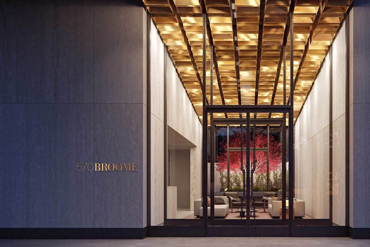 570 Broome entrance beneath a warm geometric canopy, with the furnished lobby and red-leaved courtyard beyond.