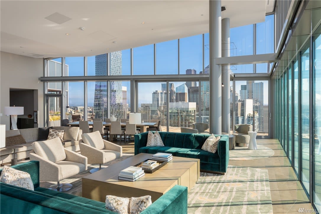 Modern condo living room with floor-to-ceiling windows offering a panoramic view of a vibrant city skyline.