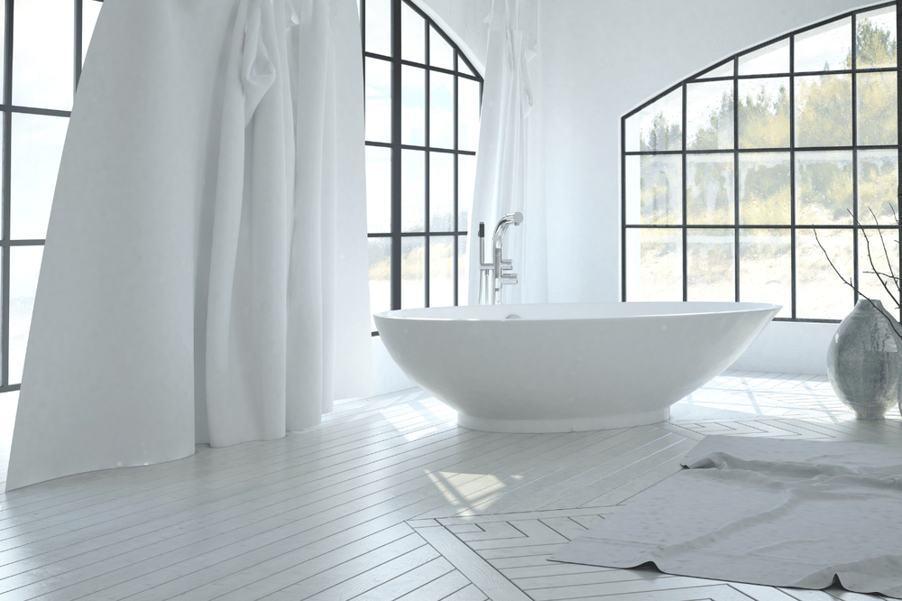 Luxury bathroom with a freestanding tub beneath large black-framed windows.