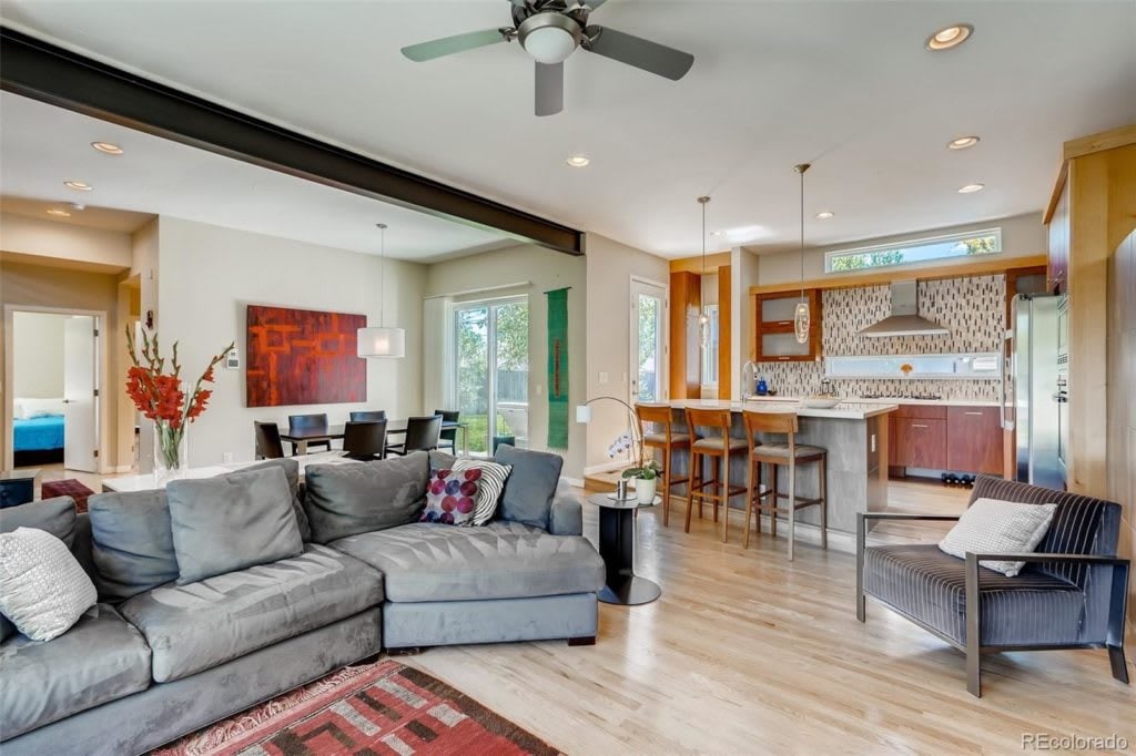 Open-plan living room with a gray sectional facing a kitchen and breakfast bar.