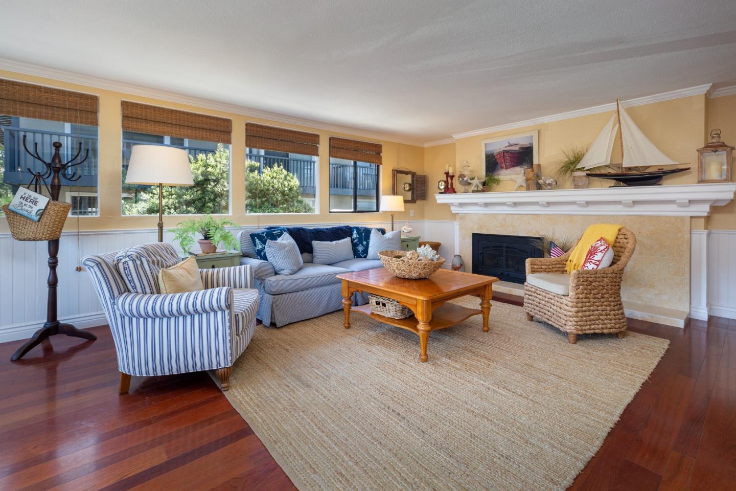 Living room with a fireplace, sailboat model on the mantel, and seating arranged around a wooden coffee table.