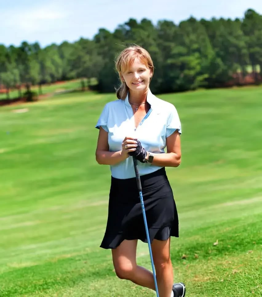 Smiling golfer on a lush course, evoking the exclusive lifestyle associated with luxury estate communities.