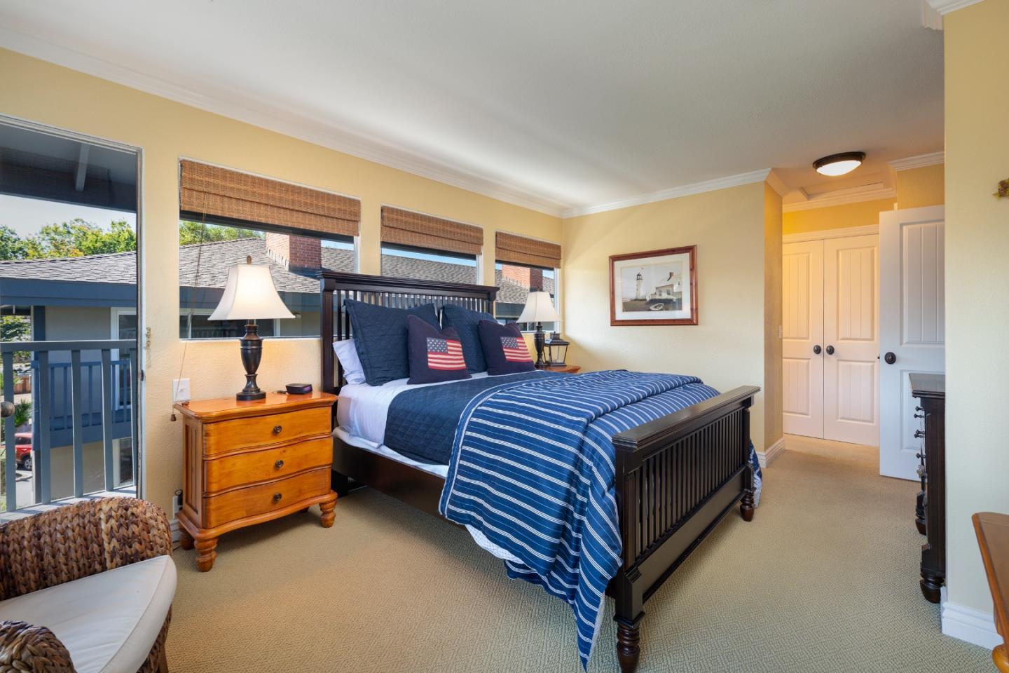 Bedroom with navy bedding, American flag pillows, and windows overlooking neighboring rooftops.