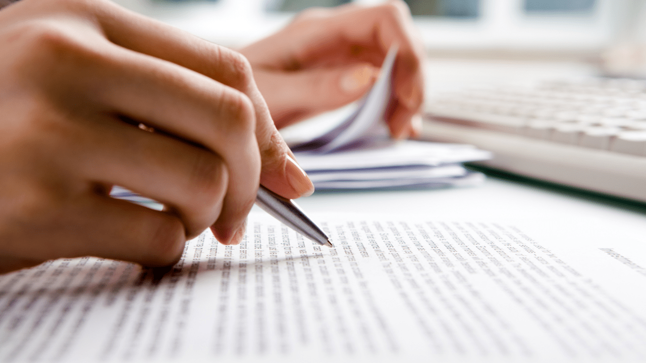 Close-up image of a hand holding a pen, writing on a paper.