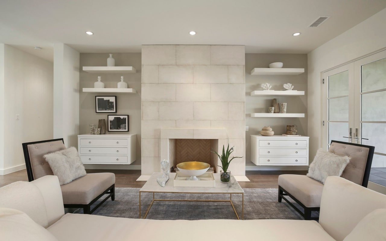 Cozy living room with a fireplace nestled in a stone wall, complemented by a comfortable seating area and hanging shelves.