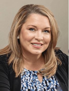 Melissa Stewart smiling in a black jacket and blue-and-white patterned blouse.
