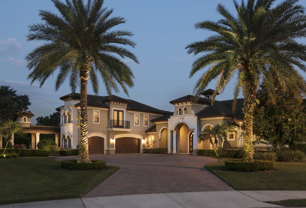 A magnificent luxury estate with a sweeping driveway and welcoming warm lights.