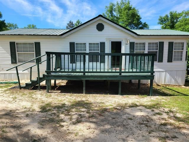 A house in 533 N Forest Dr  elevated on stilts with a spacious front deck. The yard is mostly sandy with some patches of grass, and it is surrounded by trees.