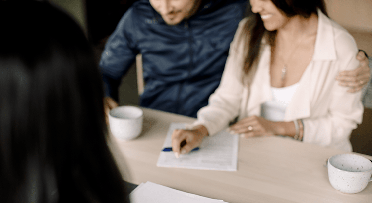 A couple sitting at a table, reviewing documents with another person.