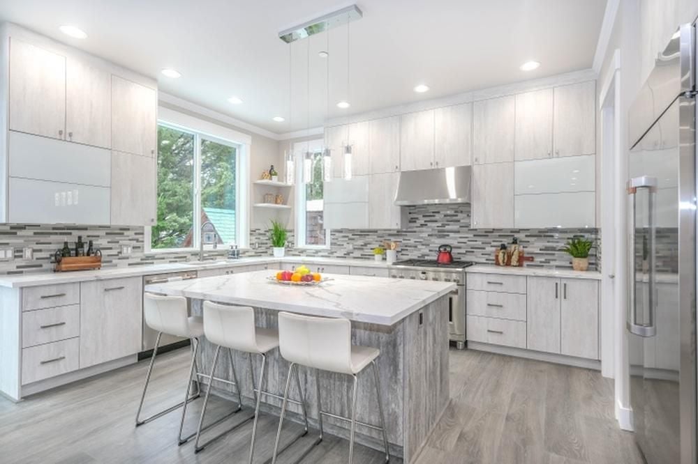 Bright modern kitchen with white cabinetry, a large island, bar stools, and stainless steel appliances.
