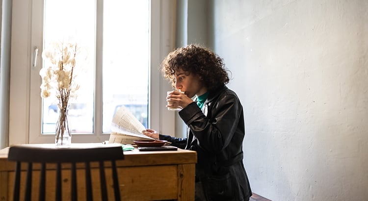 woman in a coffee shop reading a newspaper