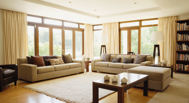 A cozy living room featuring a couch, coffee table, bookcase, and a window allowing natural light to enter.