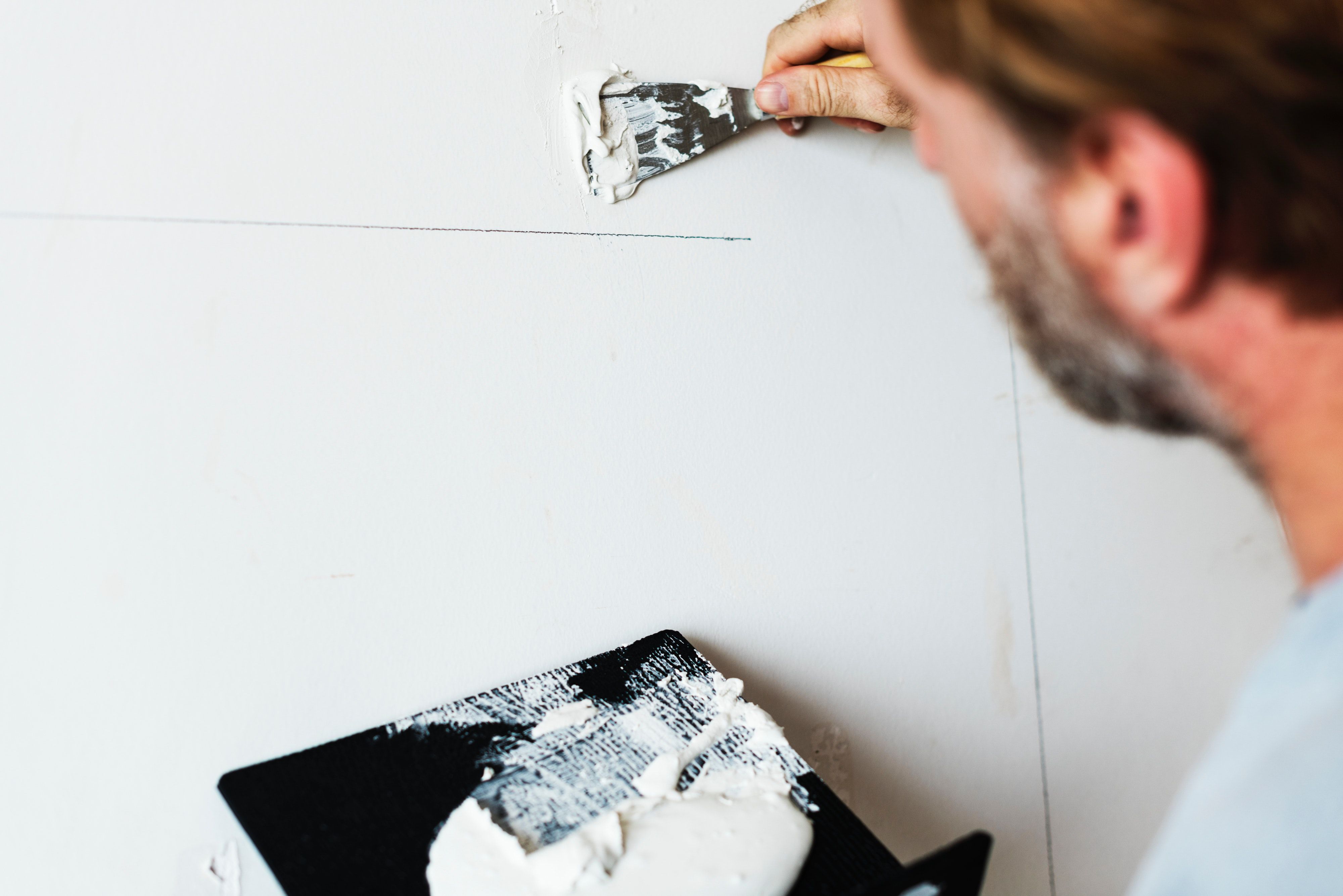 A man applies joint compound to a wall seam with a putty knife.