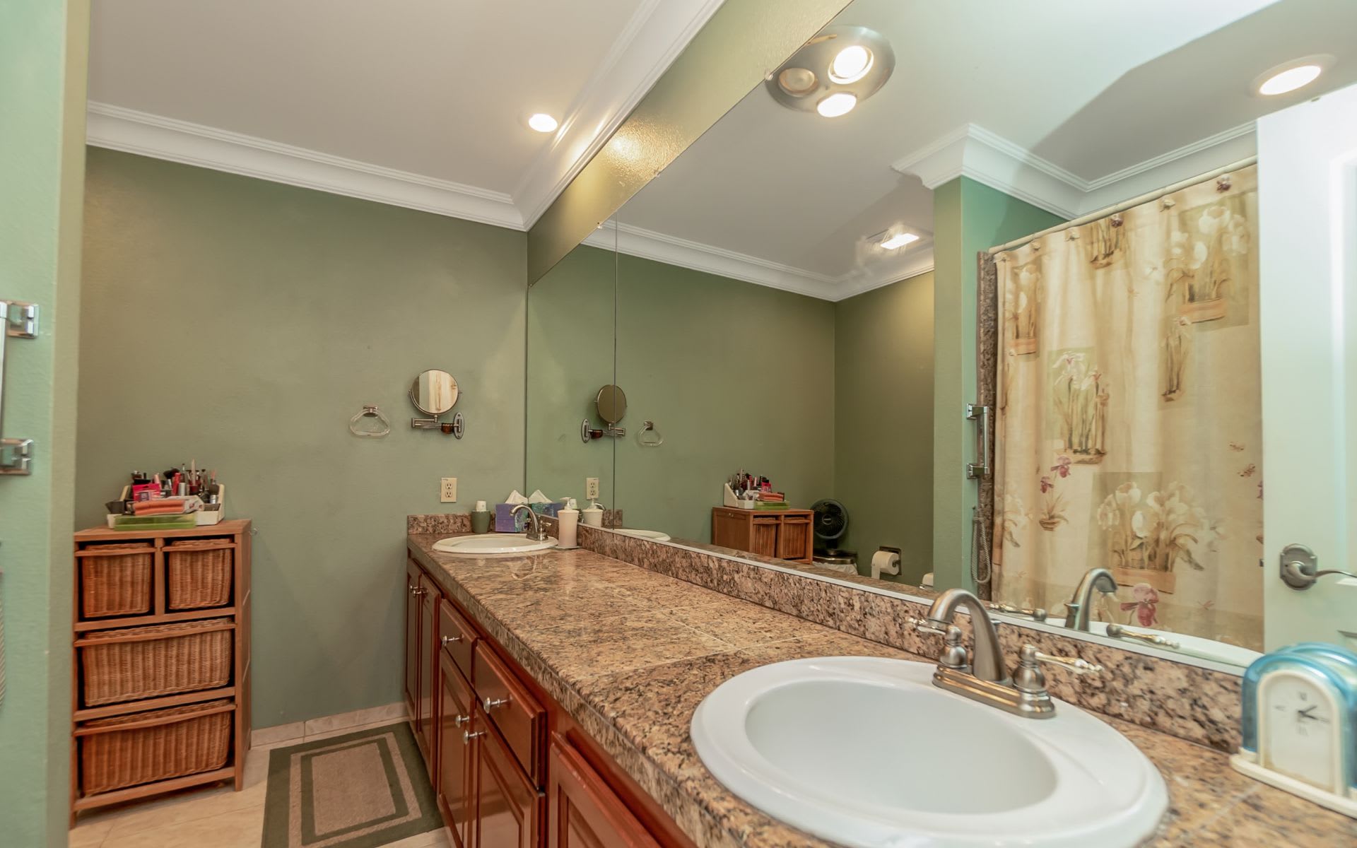 Bathroom with a granite vanity, large mirror, and patterned shower curtain.