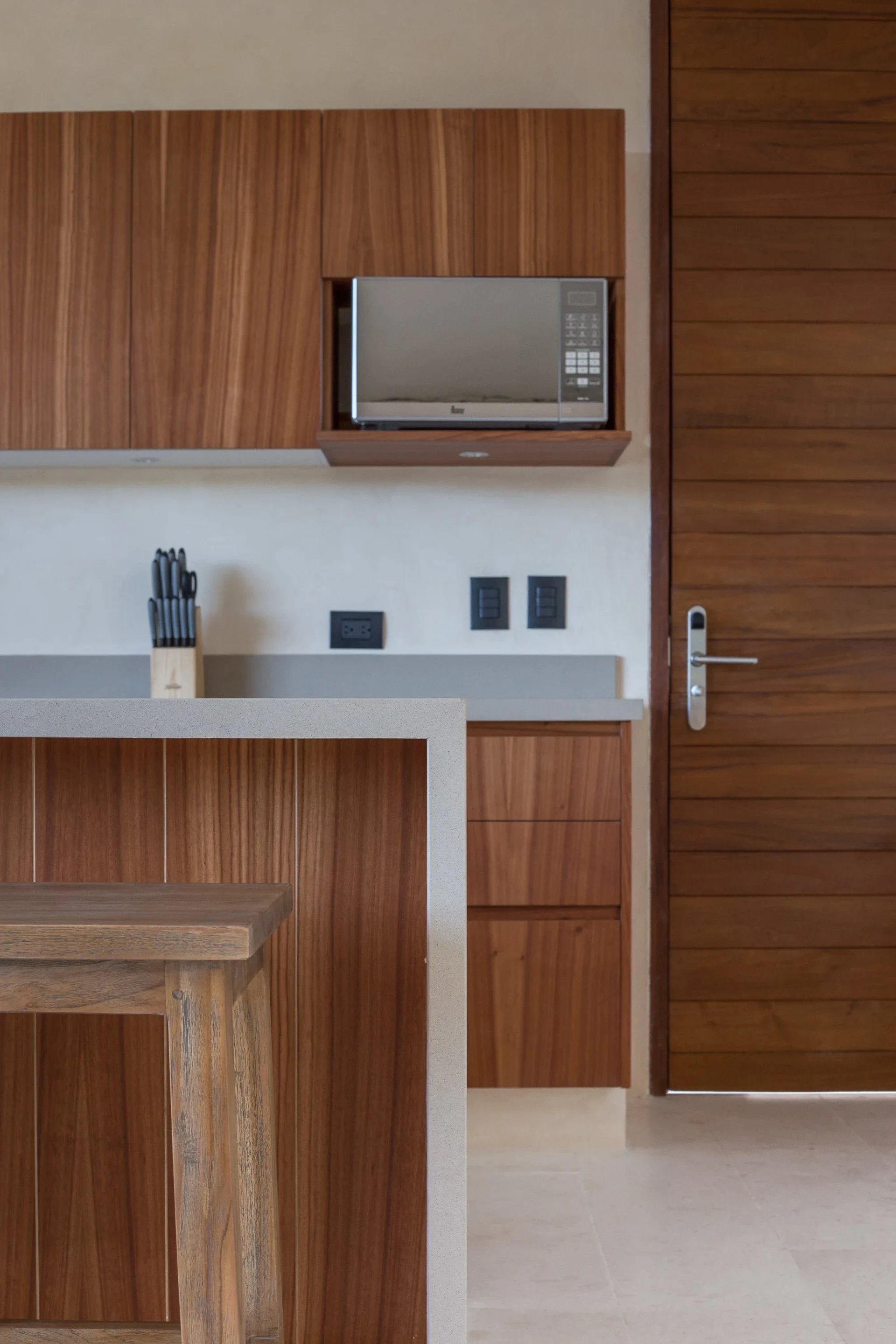Kitchen with warm wood cabinetry, built-in microwave, stone counters, and a wood dining table.