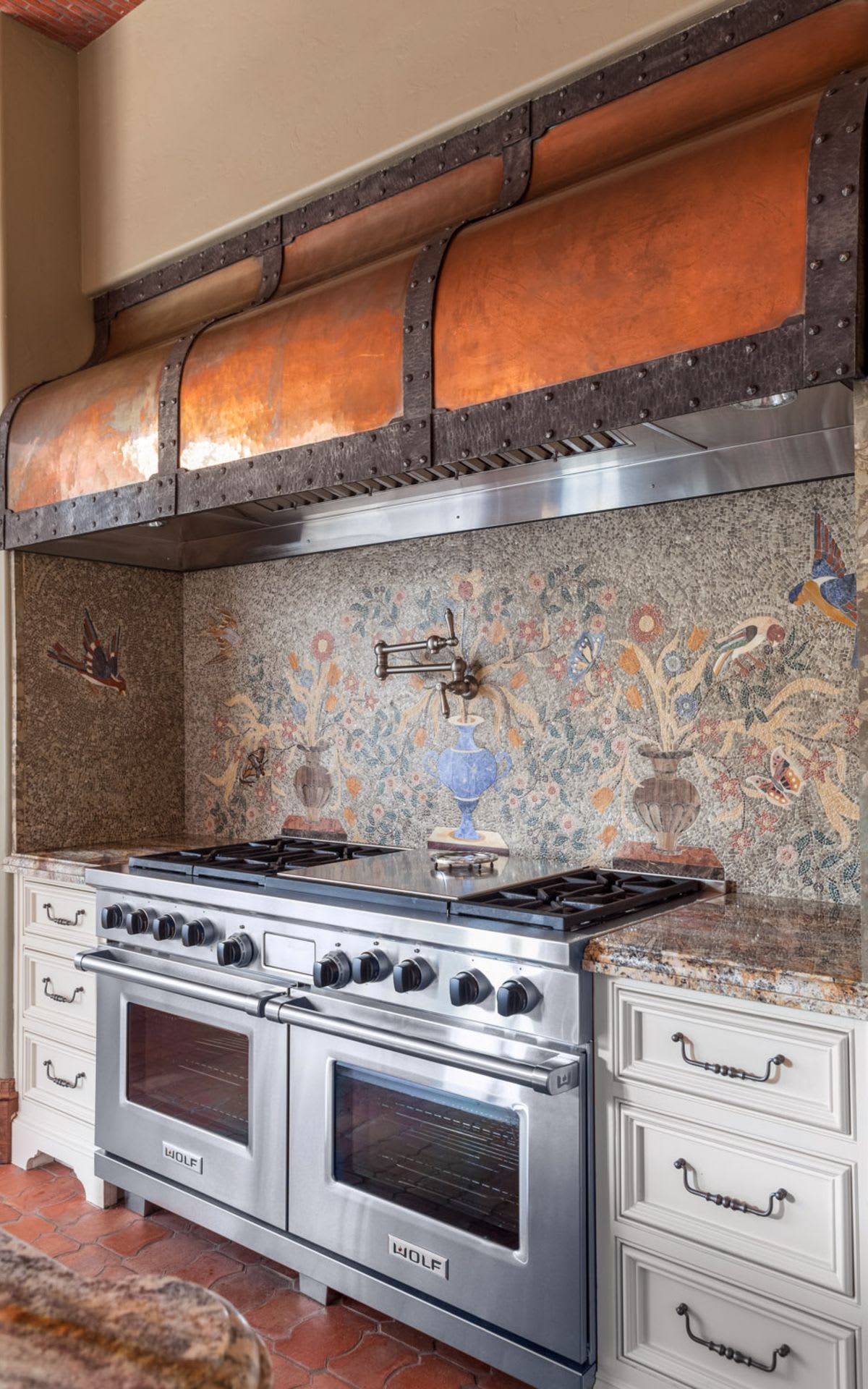 Stunning kitchen with intricate mosaic backsplash, paired with stylish bronze range hood for a touch of elegance and warmth.