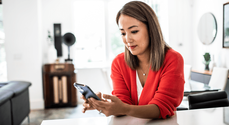 woman in red shirt looking at phone at kitchen bar