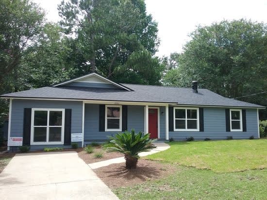 A single-story house with a neatly trimmed lawn and a few decorative plants in the front yard.