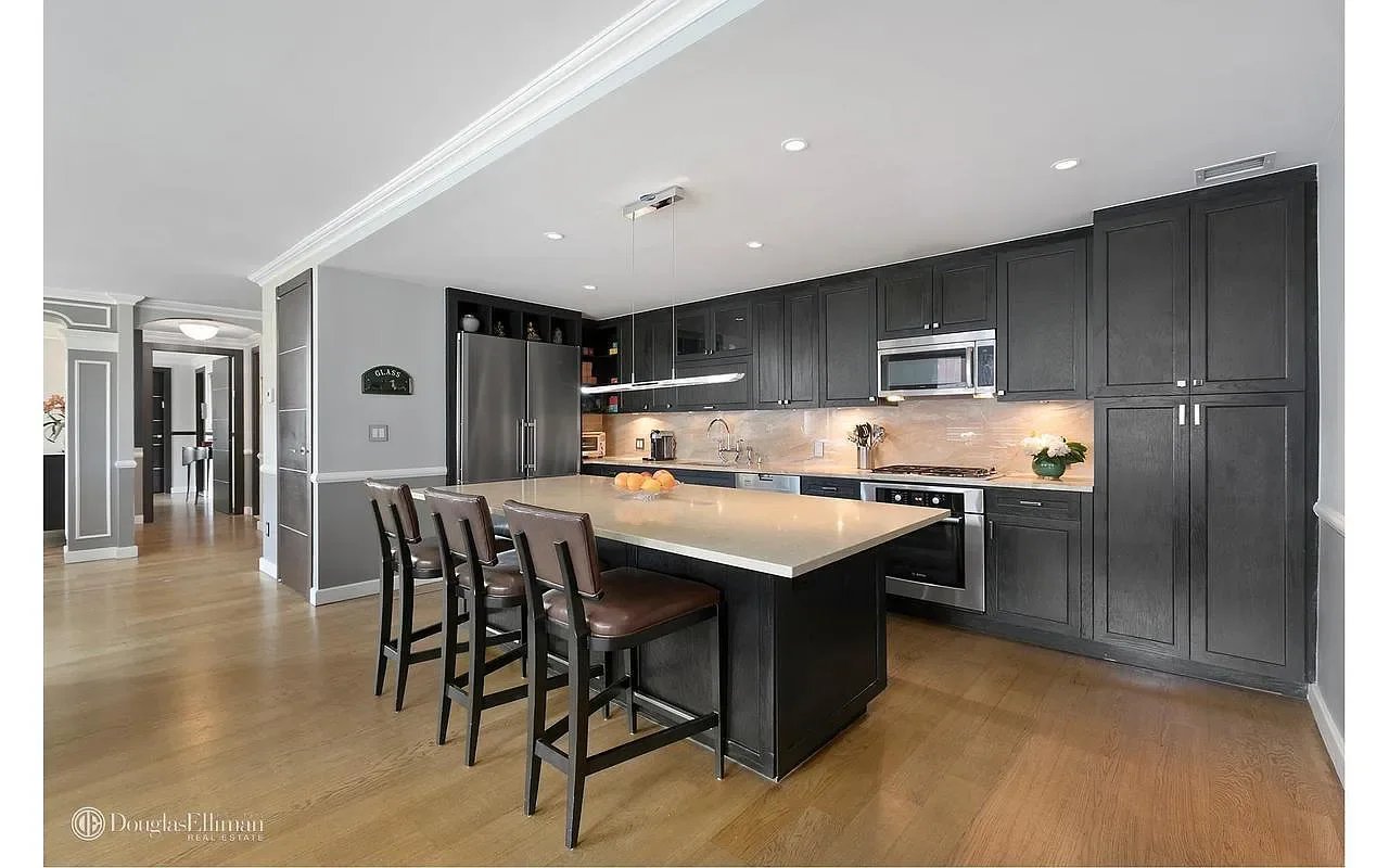 Kitchen with dark cabinetry, stainless steel appliances, and a large island with bar seating.