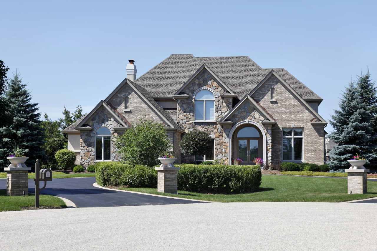 Large brick and stone house with a driveway in a residential area of League City, Texas.